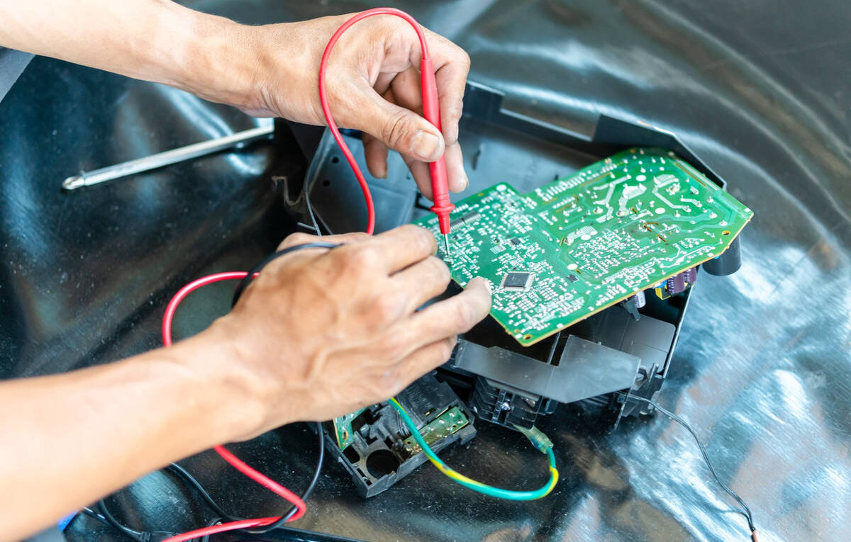 Técnico usando multímetro para diagnosticar curto na placa de ar-condicionado