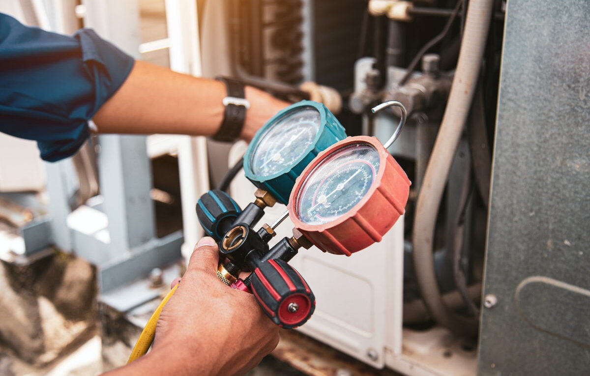 Técnico refrigerista utilizando vacuômetro micron gauge durante evacuação de sistema de ar-condicionado
