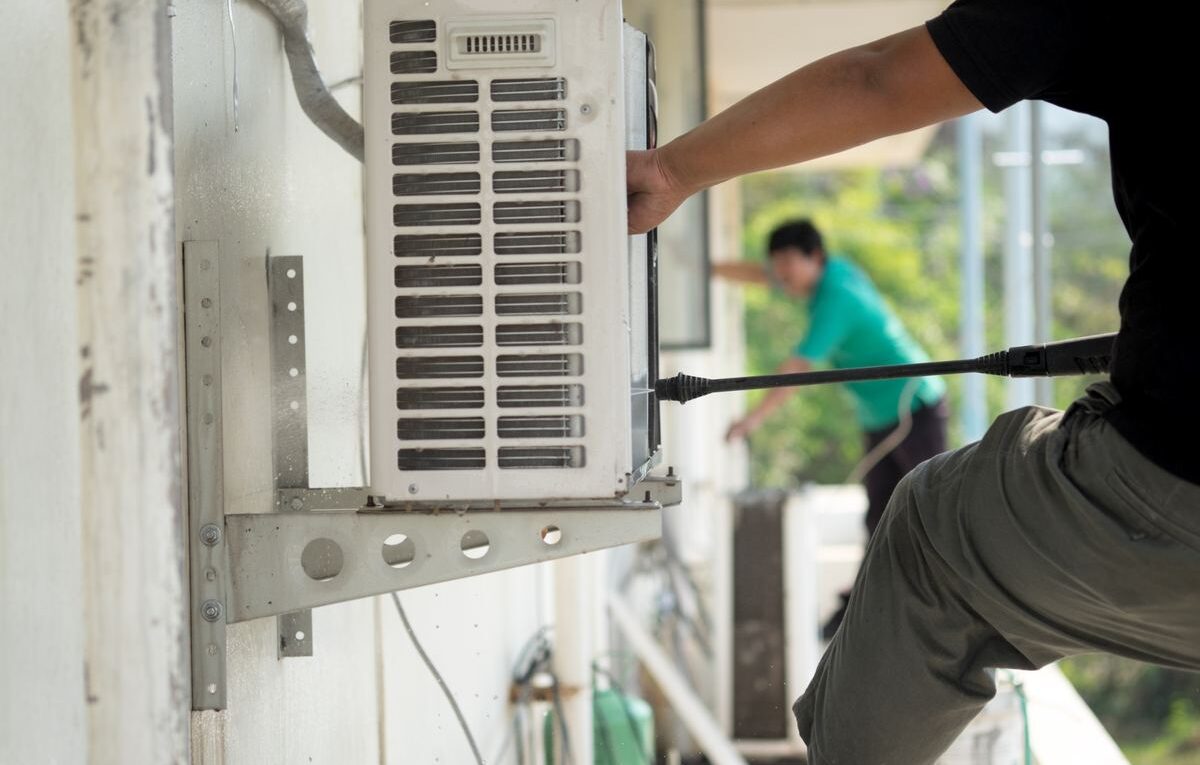 Técnico realizando a instalação de ar-condicionado em parede externa com suporte metálico