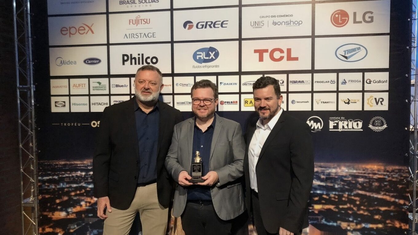 Representantes da Frigelar recebendo o Troféu Oswaldo Moreira 2026 no palco com logos de marcas parceiras