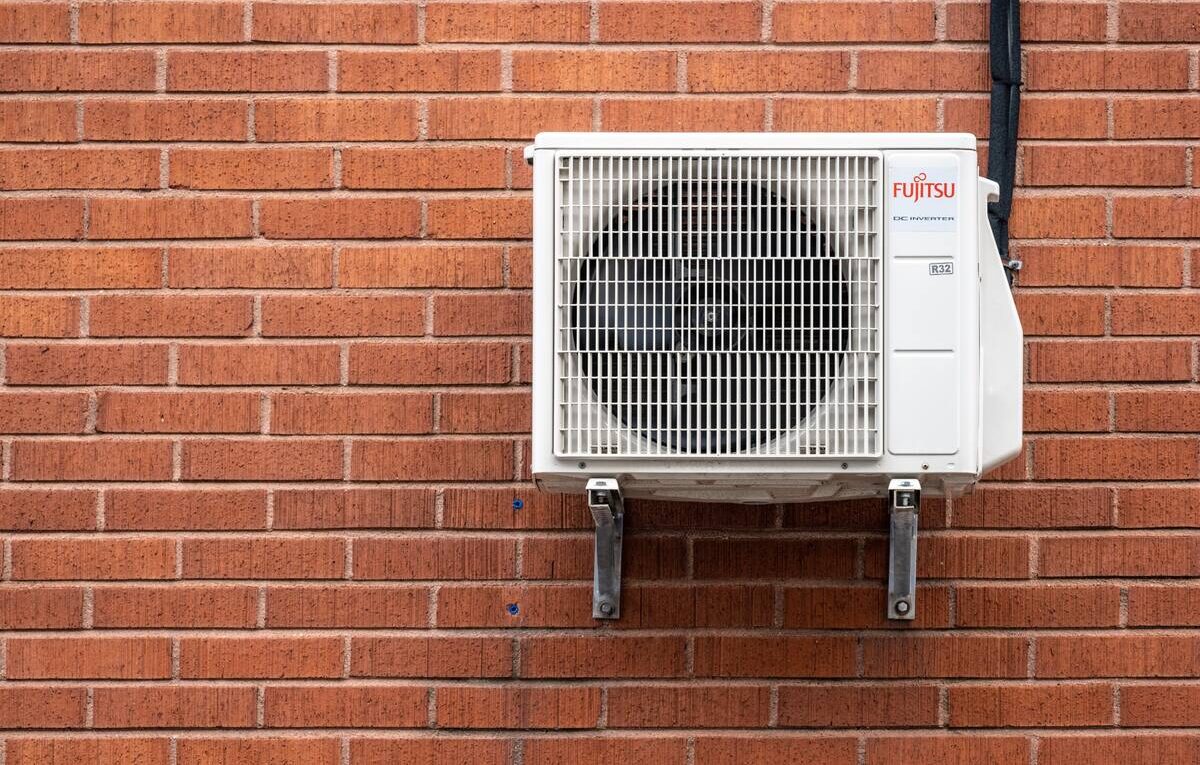 Unidade externa de ar-condicionado Fujitsu instalada em parede de tijolos, usada para ilustrar o diagnóstico de códigos de erro.