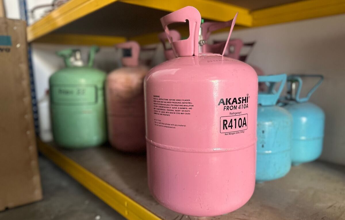 Cilindro rosa de gás refrigerante R410A armazenado em prateleira com outros cilindros.