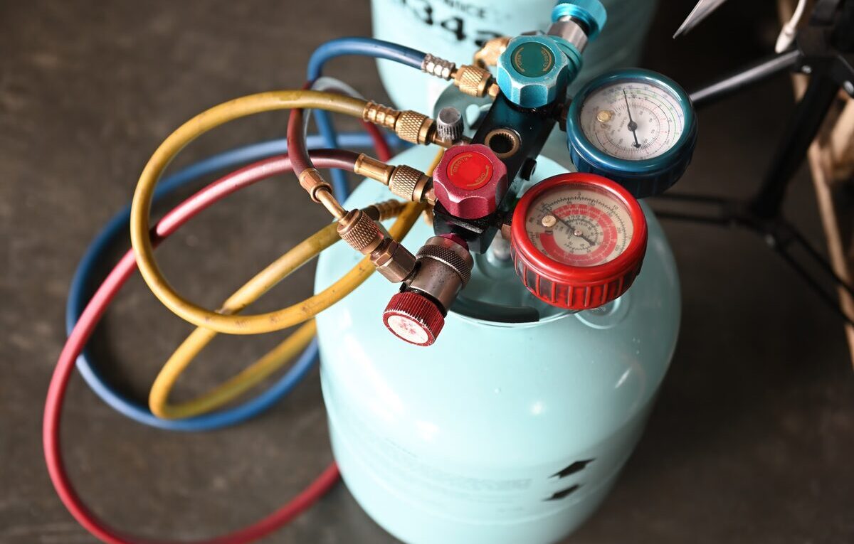 Manifold com mangueiras conectado a cilindro de fluido refrigerante durante diagnóstico de contaminação