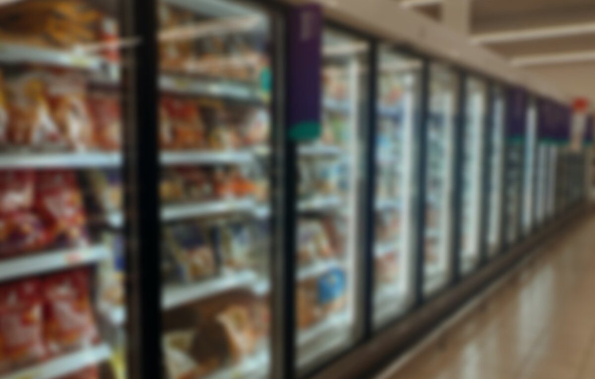 Fileira de expositores verticais com portas de vidro e produtos em um corredor de supermercado.